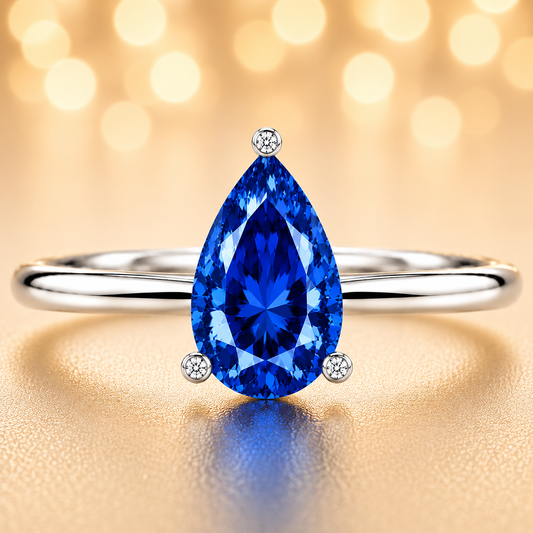 Royal blue sapphire engagement ring with a 6×4 mm pear-cut center stone, crafted in white gold plated 925 silver. Available now at BSI Jewelry.