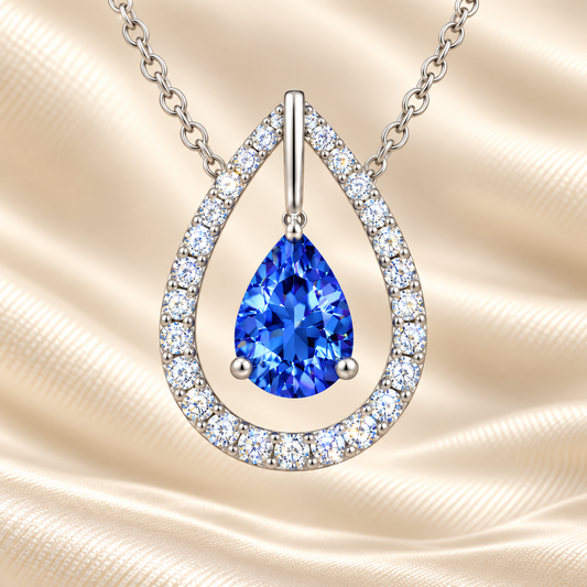 Blue sapphire necklace with a 7×5 mm pear cut and moissanite halo, crafted in white gold-plated 925 silver. Elegant and refined. Available now at BSI Jewelry.