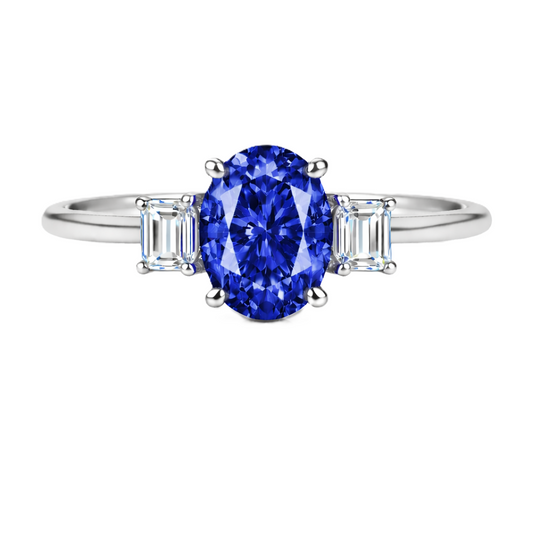Blue sapphire ring with 7×5 mm oval center and 5×3 mm moissanite sides in white gold-plated 925 silver. Elegant and refined. Available now at BSI Jewelry.