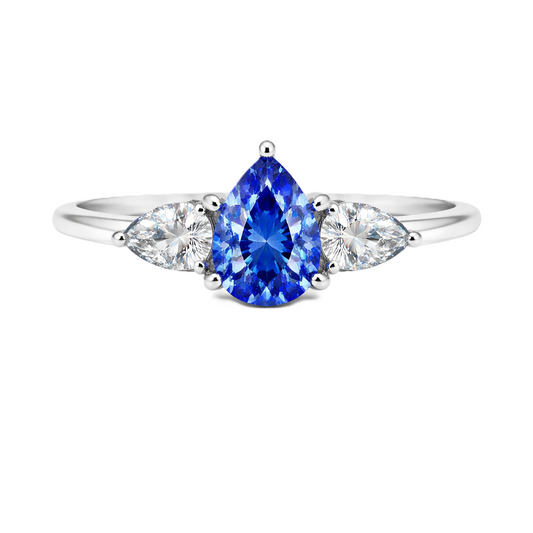 Blue sapphire ring with 7×5 mm pear center and side stones in white gold-plated 925 silver. Elegant and timeless for daily wear. Available now at BSI Jewelry.
