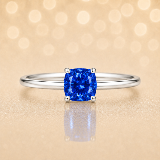 Blue sapphire solitaire ring with a 5 mm cushion gemstone set in white gold-plated 925 silver. Elegant and timeless design. Available now at BSI Jewelry.