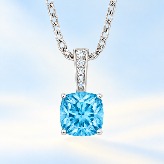 Swiss blue topaz cushion pendant in white gold-plated 925 silver with moissanite accents. Elegant and hypoallergenic. Available now at BSI Jewelry.