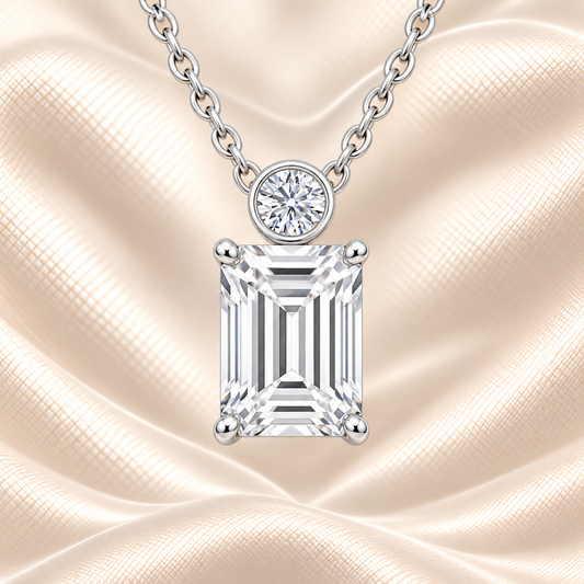 Emerald cut Moissanite pendant with 7×5 mm center stone and bezel-set round accent in white gold plated 925 silver. Elegant everyday luxury by BSI Jewelry.