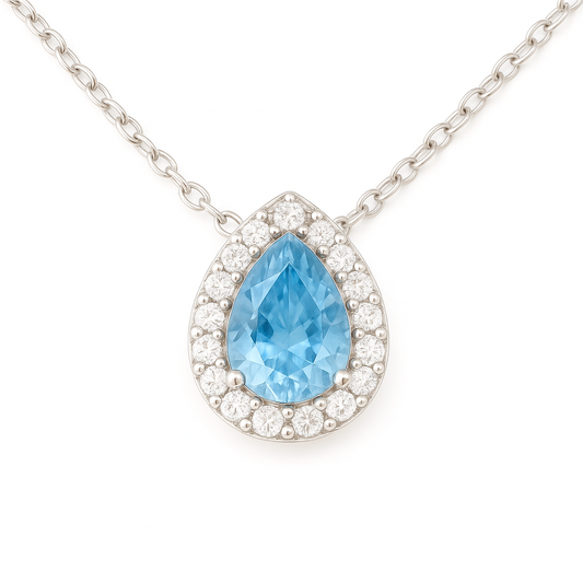 Elegant 7×5 mm blue sapphire halo necklace accented with Moissanite, crafted in white gold-plated 925 silver and palladium alloy. Available now at BSI Jewelry.