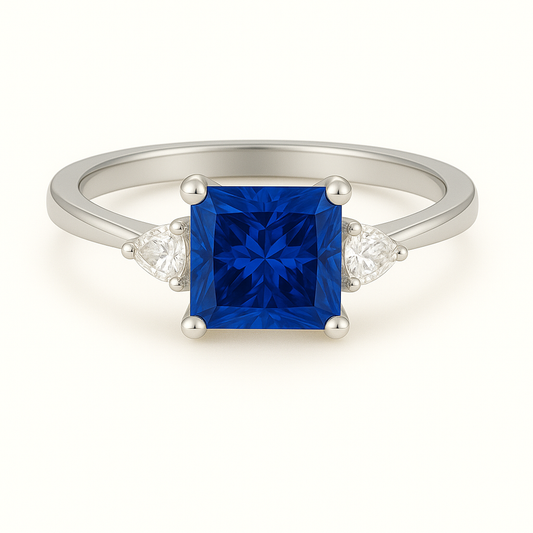 6 mm princess-cut blue sapphire ring with Moissanite accents in white-gold-plated 925 silver. Radiant sparkle and timeless elegance. Available at BSI Jewelry.