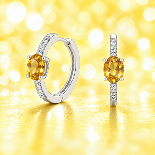Elegant oval-cut citrine huggie earrings in white gold-plated 925 silver with sparkling Moissanite accents for a warm, golden glow. Available now at BSI Jewelry.