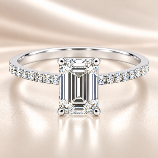 Moissanite emerald ring with a 7×5 mm emerald-cut stone, accented by moissanite in white gold-plated 925 silver. Sleek and elegant. Available now at BSI Jewelry.