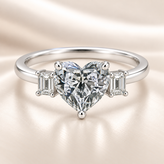 Moissanite engagement ring with 6 mm heart center and emerald accents in white gold-plated 925 silver. Elegant and hypoallergenic. Available now at BSI Jewelry.