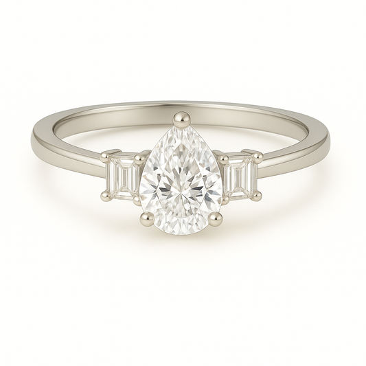 Moissanite engagement ring with 7×5 mm pear center and emerald-cut accents in white gold-plated 925 silver. Elegant and hypoallergenic. Available now at BSI Jewelry.