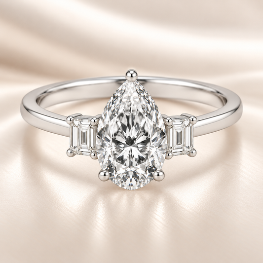 Moissanite engagement ring with 7×5 mm pear center and emerald-cut accents in white gold-plated 925 silver. Elegant and hypoallergenic. Available now at BSI Jewelry.