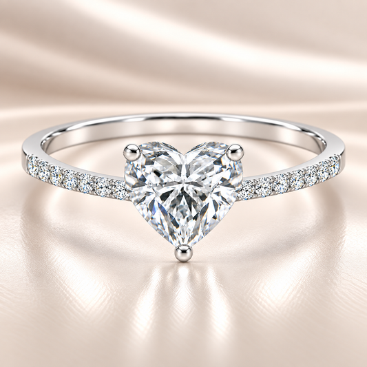 Moissanite heart ring with a 6 mm heart-cut stone, accented by moissanite in white gold-plated 925 silver. Romantic and elegant. Available now at BSI Jewelry.