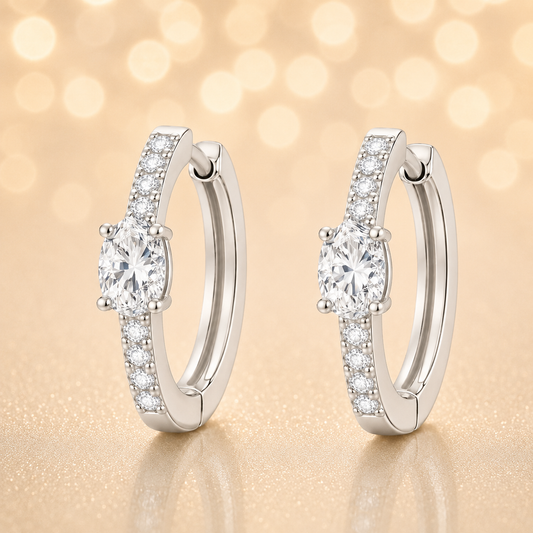Moissanite huggie earrings, 5×3 mm oval cut in white gold plated 925 silver. Elegant pavé hoop design with brilliant sparkle. Available now at BSI Jewelry.