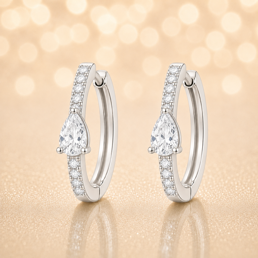 Moissanite huggie earrings, 5×3 mm pear cut in white gold plated 925 silver. Elegant pavé hoop design with brilliant sparkle. Available now at BSI Jewelry.