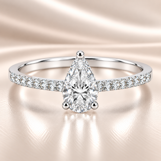 Moissanite pear ring with a 7×5 mm pear-cut stone, accented by moissanite in white gold-plated 925 silver. Elegant and timeless. Available now at BSI Jewelry.