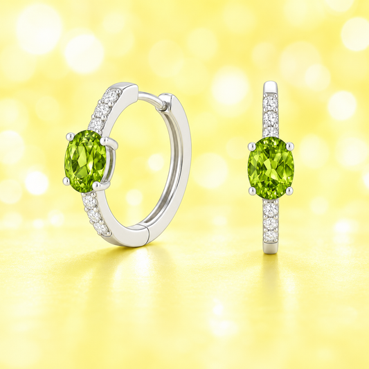 Elegant oval-cut peridot huggie earrings in white gold-plated 925 silver with sparkling Moissanite accents for fresh green charm. Available now at BSI Jewelry.