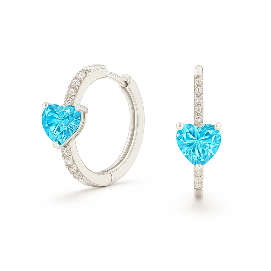 Heart-cut Swiss Blue Topaz huggie earrings in white-gold-plated 925 silver with sparkling Moissanite accents for bright blue brilliance. Available at BSI Jewelry.