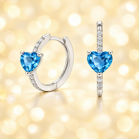 Heart-cut Swiss Blue Topaz huggie earrings in white-gold-plated 925 silver with sparkling Moissanite accents for bright blue brilliance. Available at BSI Jewelry.