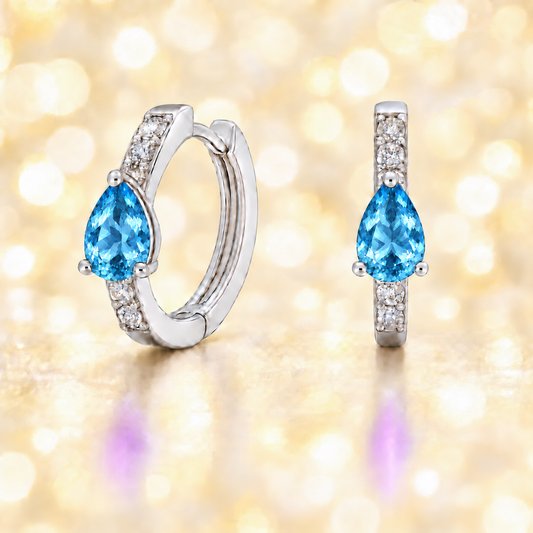Elegant pear-cut Swiss blue topaz huggie in white gold-plated 925 silver with Moissanite accents for fresh, versatile sparkle. Available now at BSI Jewelry.