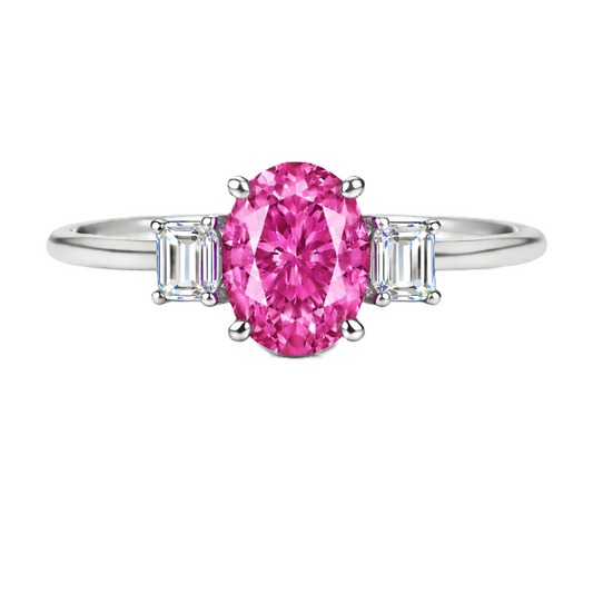 Pink sapphire ring with 7×5 mm oval center and 5×3 mm moissanite sides in white gold-plated 925 silver. Elegant and refined. Available now at BSI Jewelry.