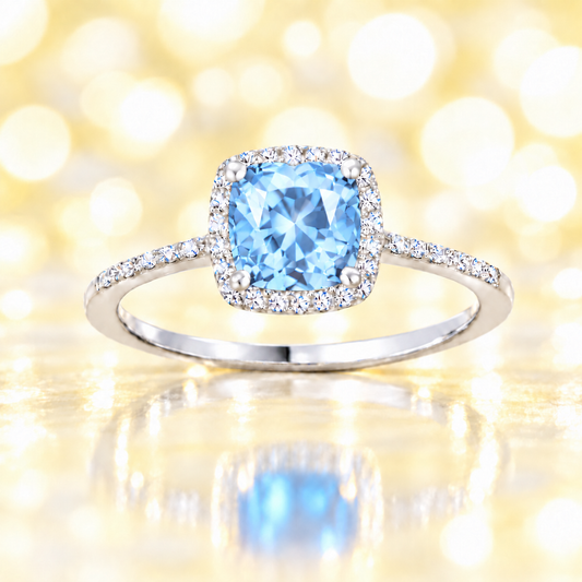Sky blue topaz ring with a 6 mm cushion-cut center in white gold-plated 925 silver, accented with moissanite. Available now at BSI Jewelry.