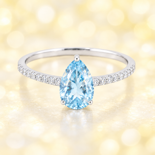 Sky blue topaz ring with a 7×5 mm pear-cut stone and moissanite accents in white gold plated 925 silver. Elegant for daily wear. Available now at BSI Jewelry.