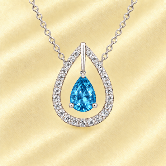 Swiss blue topaz necklace with a 7×5 mm pear-cut in white gold-plated 925 silver, accented by a moissanite halo. Elegant and refined. Available now at BSI Jewelry