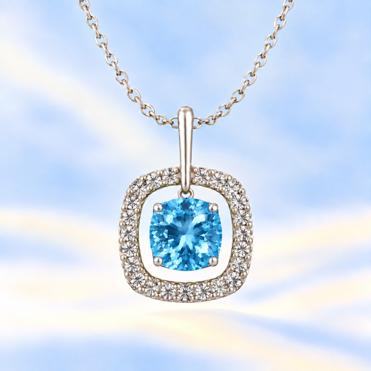 Swiss blue topaz pendant with a 7 mm cushion-cut in white gold-plated 925 silver, accented by a moissanite halo. Elegant and refined. Available now at BSI Jewelry.