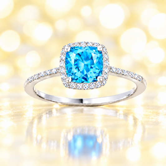 Swiss blue topaz ring with a 6 mm cushion-cut center in white gold-plated 925 silver, accented with moissanite for refined sparkle. Available now at BSI Jewelry.
