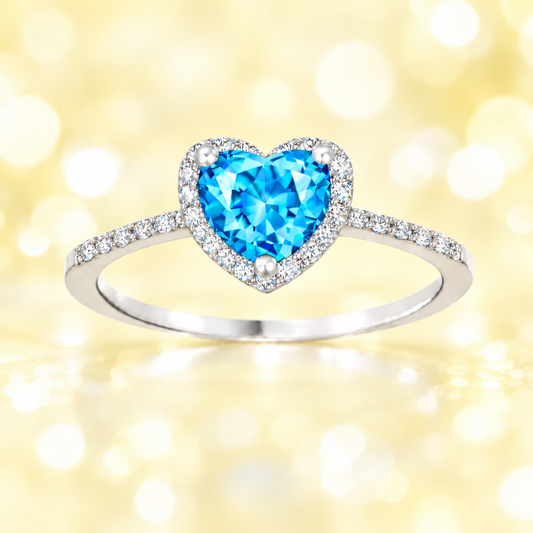 Swiss blue topaz ring with a 6 mm heart cut, crafted in white gold-plated 925 silver and accented with moissanite. Available now at BSI Jewelry.