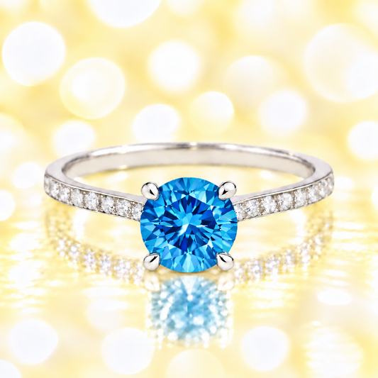 Swiss blue topaz ring with a 6 mm round-cut and moissanite accents, crafted in white gold-plated 925 silver. Elegant for daily wear. Available now at BSI Jewelry.