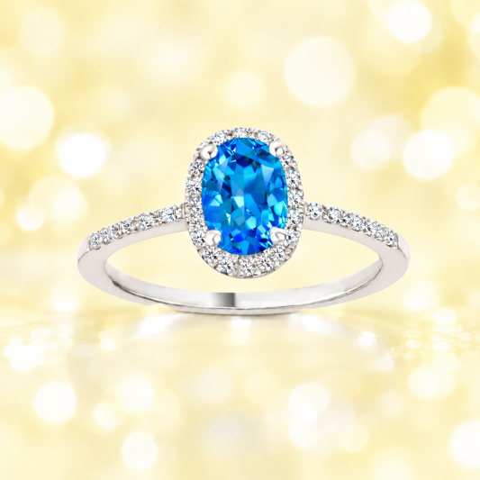 Swiss blue topaz ring with a 7×5 mm oval cut in white gold-plated 925 silver, with moissanite. Elegant and refined for daily wear. Available now at BSI Jewelry.