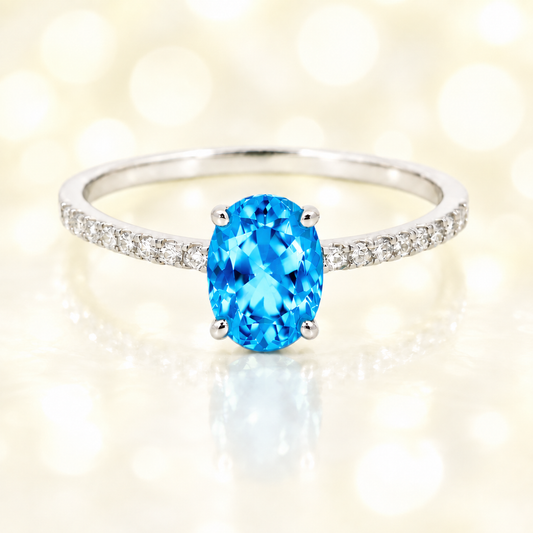 Swiss blue topaz ring with a 7×5 mm oval-cut stone and moissanite accents in white gold plated 925 silver. Elegant for daily wear. Available now at BSI Jewelry.