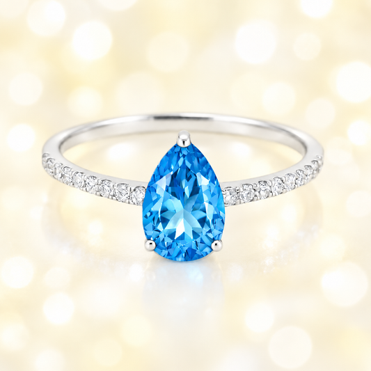 Swiss blue topaz ring with a 7×5 mm pear-cut stone and moissanite accents in white gold plated 925 silver. Elegant for daily wear. Available now at BSI Jewelry.